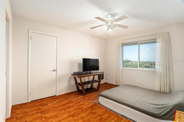 bedroom featuring ceiling fan, a textured ceiling, and light hardwood / wood-style floors