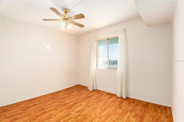 empty room with ceiling fan, light hardwood / wood-style flooring, and a textured ceiling