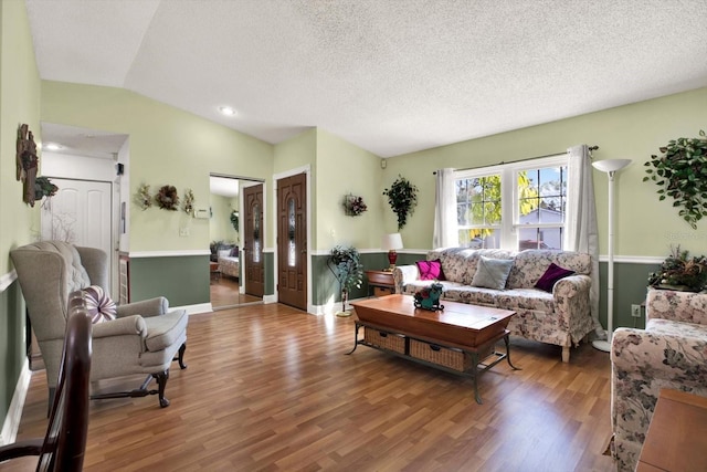 living room with a textured ceiling, hardwood / wood-style flooring, and vaulted ceiling