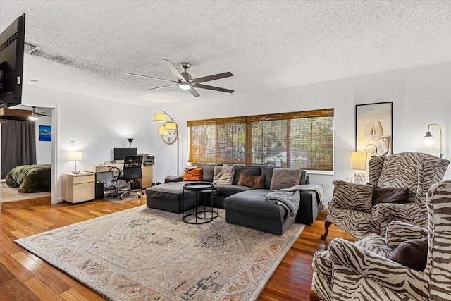 living room featuring hardwood / wood-style floors, a textured ceiling, and ceiling fan