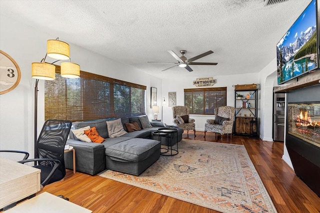 living room with dark hardwood / wood-style floors, ceiling fan, and a textured ceiling