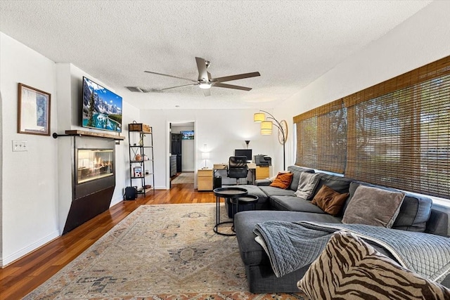 living room featuring hardwood / wood-style flooring, ceiling fan, and a textured ceiling