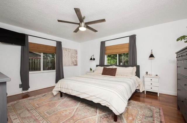 bedroom with ceiling fan, dark hardwood / wood-style flooring, and a textured ceiling