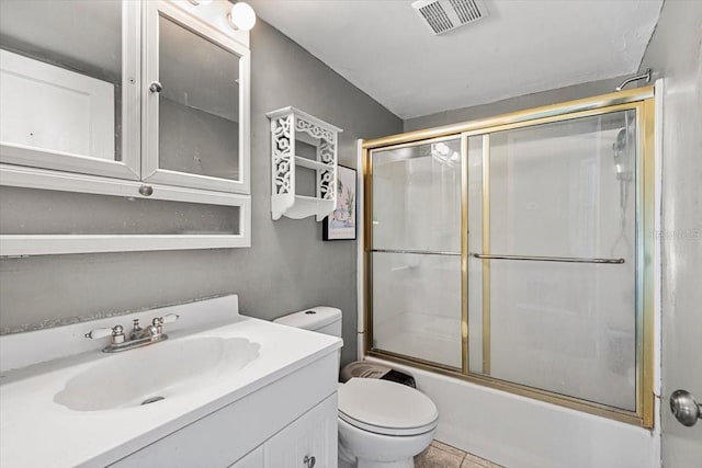 full bathroom with tile patterned flooring, vanity, bath / shower combo with glass door, and toilet