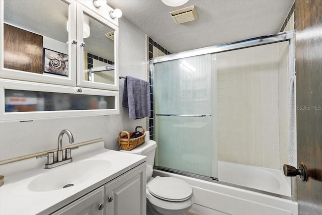 full bathroom featuring vanity, toilet, combined bath / shower with glass door, and a textured ceiling