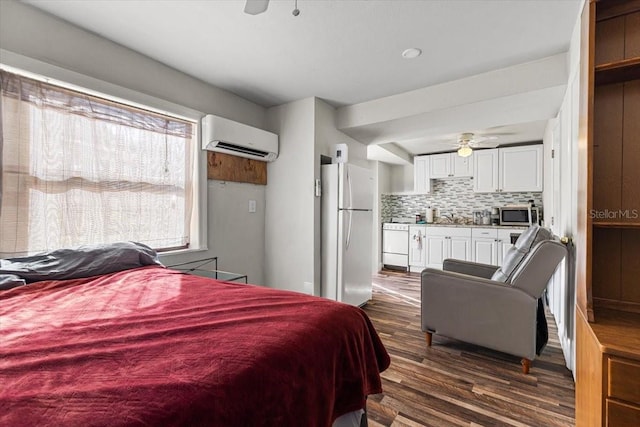 bedroom featuring ceiling fan, white fridge, an AC wall unit, and dark wood-type flooring