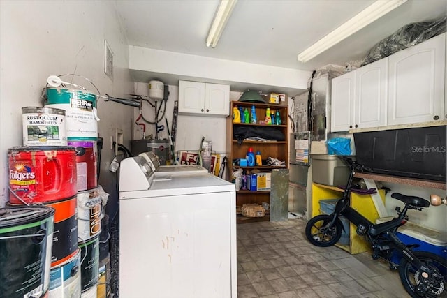 washroom featuring water heater, cabinets, and washing machine and clothes dryer