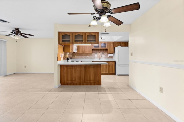 kitchen featuring kitchen peninsula, light tile patterned floors, white appliances, and backsplash