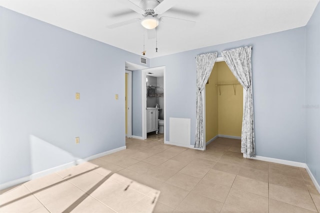 unfurnished bedroom featuring ceiling fan, a walk in closet, light tile patterned floors, and a closet