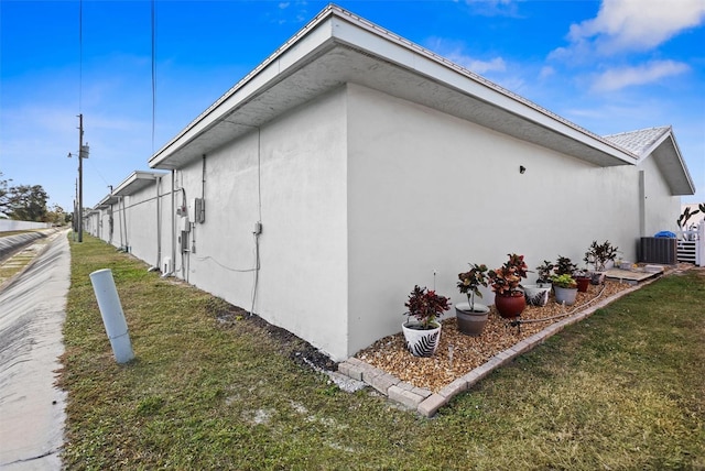 view of side of home with a yard and cooling unit