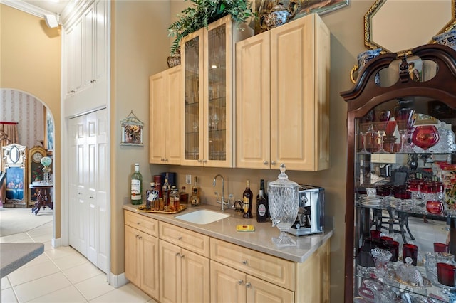 kitchen with light tile patterned flooring, ornamental molding, sink, and light brown cabinets