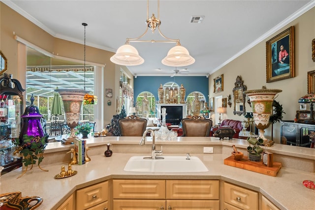 kitchen with ceiling fan with notable chandelier, crown molding, sink, light brown cabinets, and hanging light fixtures