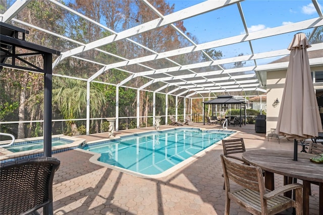 view of swimming pool with glass enclosure, a gazebo, an in ground hot tub, area for grilling, and a patio