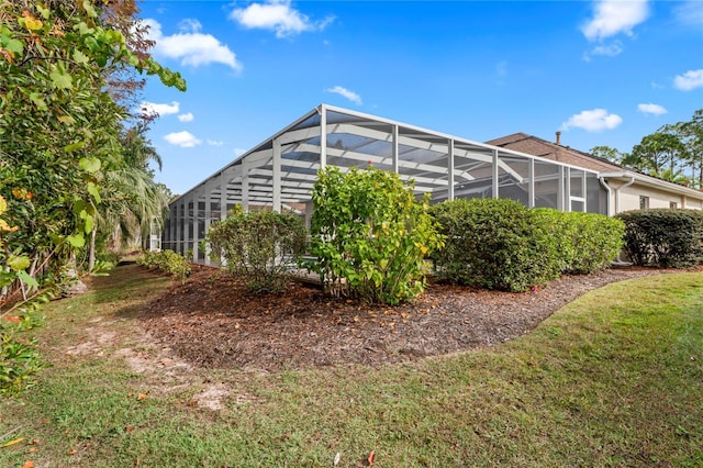 view of home's exterior with glass enclosure and a lawn