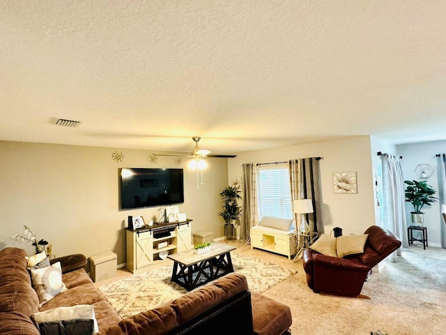 carpeted living room with ceiling fan and a textured ceiling