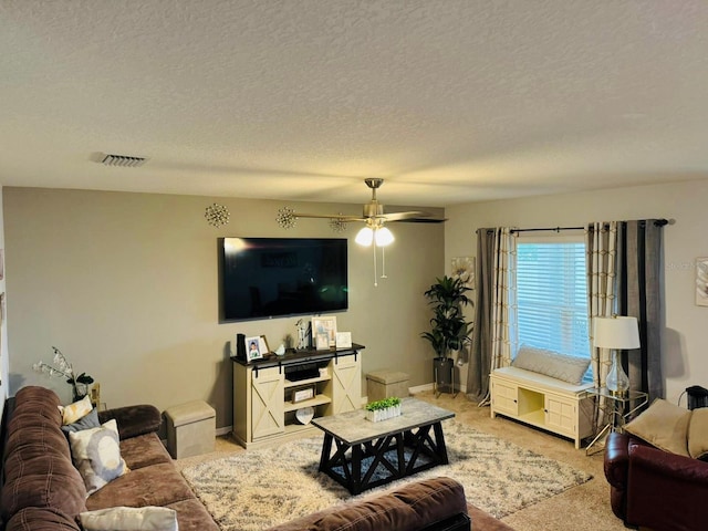 carpeted living room with ceiling fan and a textured ceiling