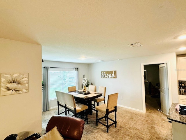 dining space featuring light carpet and a textured ceiling