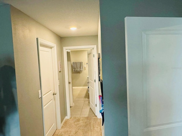 corridor featuring light tile patterned flooring and a textured ceiling