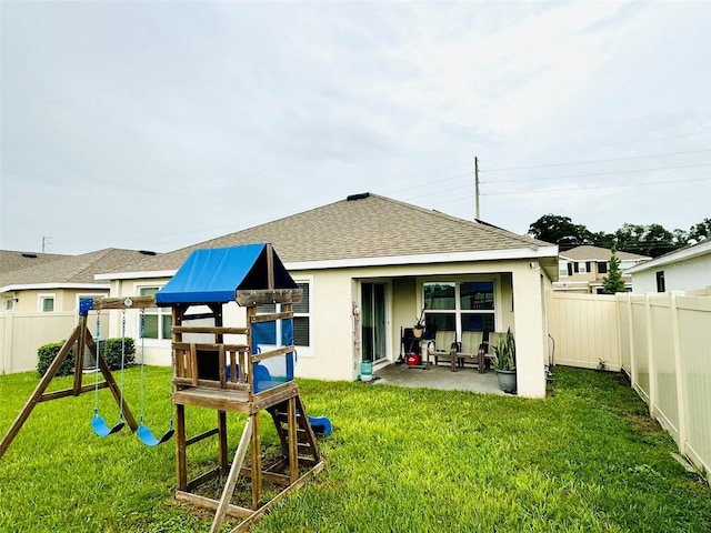 back of house featuring a playground, a patio area, and a lawn