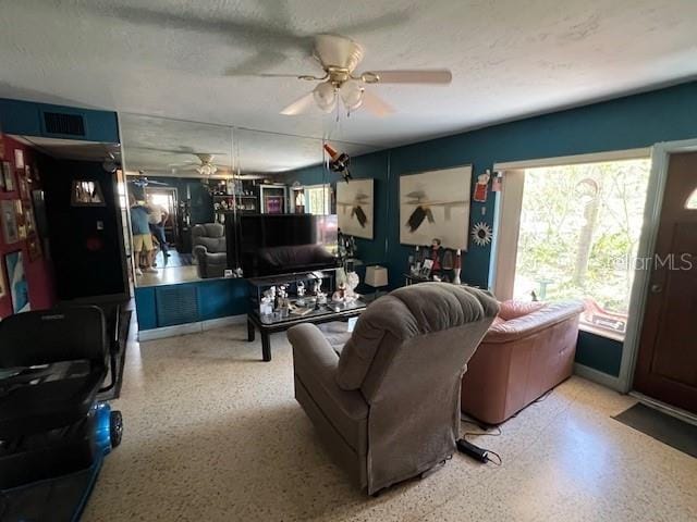 living room with ceiling fan and a textured ceiling