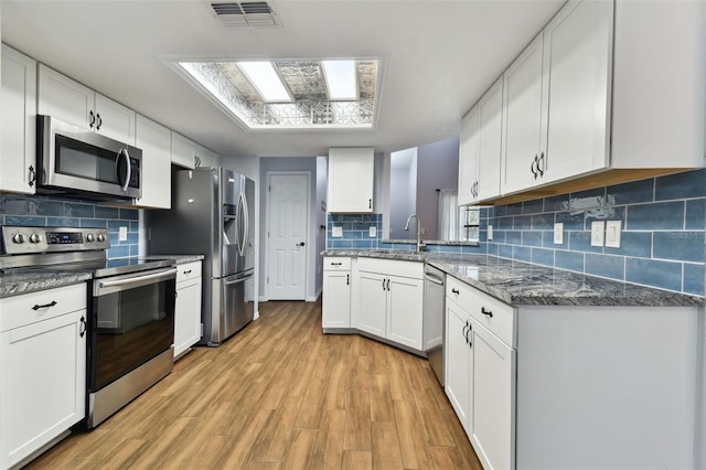 kitchen featuring backsplash, stainless steel appliances, white cabinetry, and light hardwood / wood-style floors