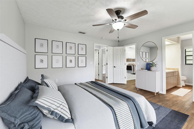 bedroom featuring a textured ceiling, connected bathroom, ceiling fan, and dark hardwood / wood-style floors