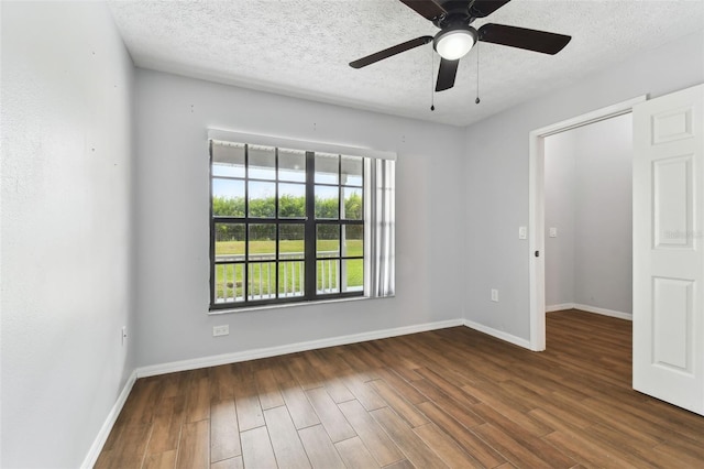 empty room with a textured ceiling, dark hardwood / wood-style floors, and ceiling fan