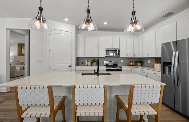 kitchen with an island with sink, white cabinets, and stainless steel appliances