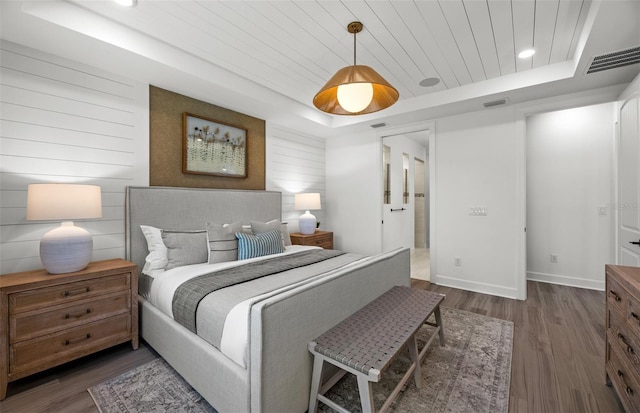 bedroom with a tray ceiling, wooden walls, wood ceiling, and dark hardwood / wood-style floors