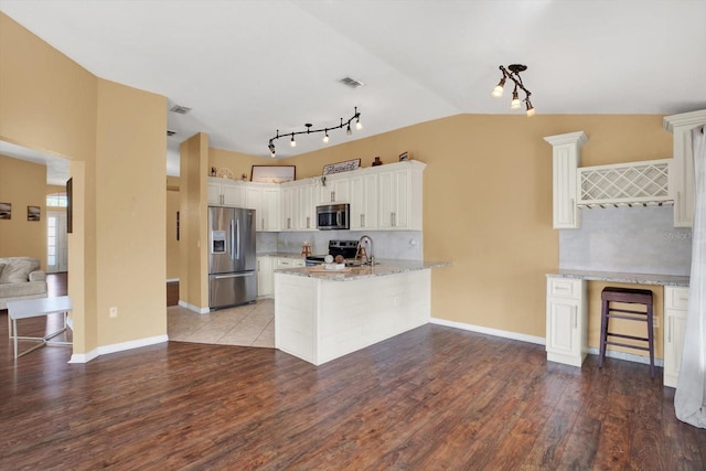 kitchen featuring white cabinetry, sink, kitchen peninsula, wood-type flooring, and appliances with stainless steel finishes