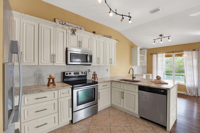 kitchen with sink, vaulted ceiling, decorative backsplash, appliances with stainless steel finishes, and kitchen peninsula