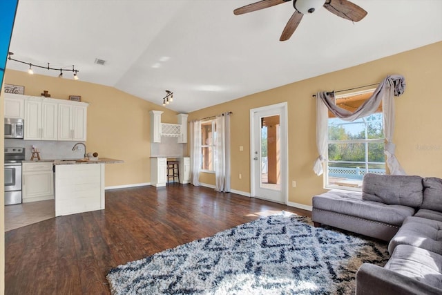 living room featuring dark hardwood / wood-style flooring, vaulted ceiling, ceiling fan, and sink