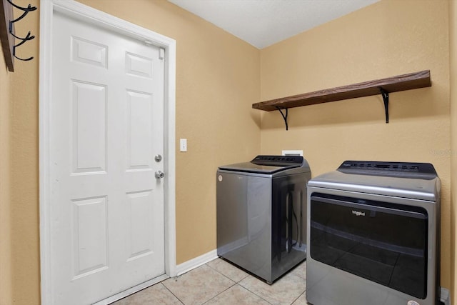 clothes washing area featuring separate washer and dryer and light tile patterned flooring