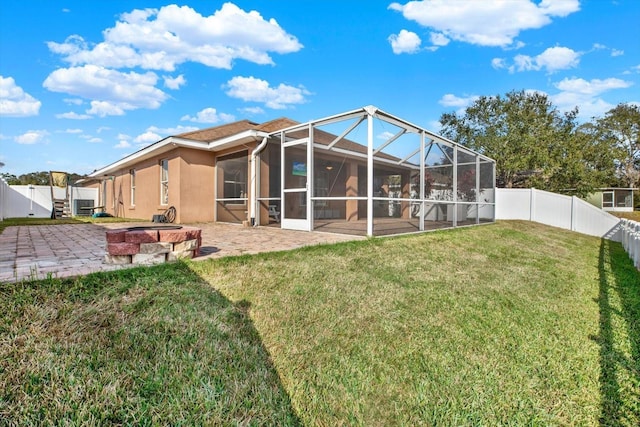 back of property with glass enclosure, a patio area, a yard, and an outdoor fire pit