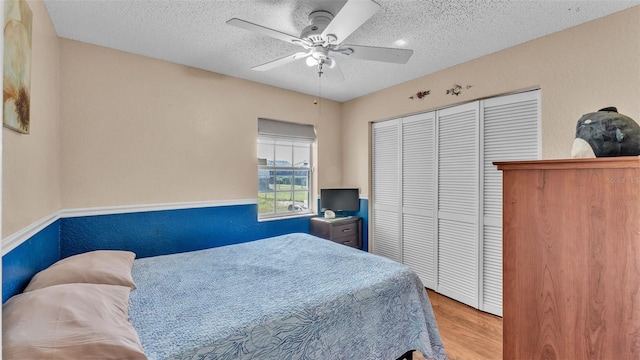 bedroom with a closet, ceiling fan, a textured ceiling, and light hardwood / wood-style flooring