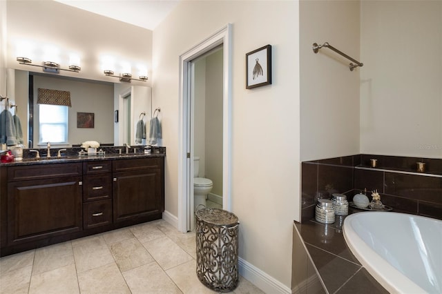 bathroom featuring tiled bath, tile patterned flooring, vanity, and toilet