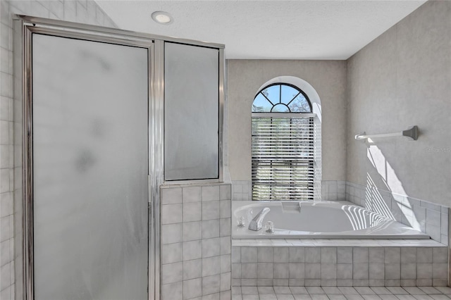 bathroom with tile patterned flooring, separate shower and tub, and a textured ceiling