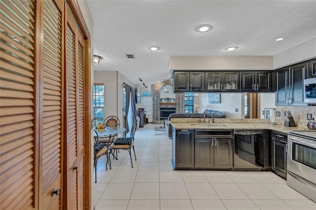 kitchen with kitchen peninsula, sink, light tile patterned floors, and stainless steel appliances