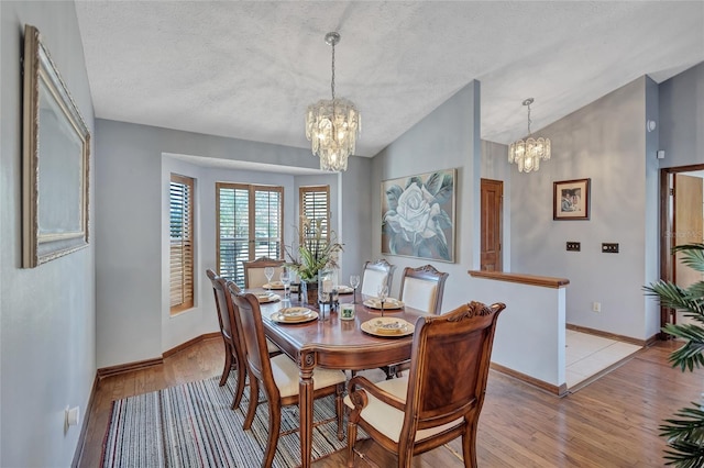 dining space featuring an inviting chandelier, lofted ceiling, and light wood-type flooring