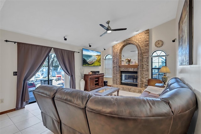 living room with ceiling fan, light tile patterned floors, a fireplace, and vaulted ceiling