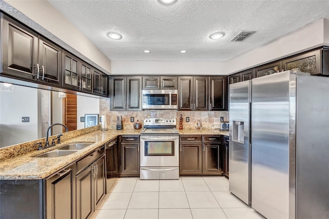 kitchen with dark brown cabinets, kitchen peninsula, sink, and appliances with stainless steel finishes