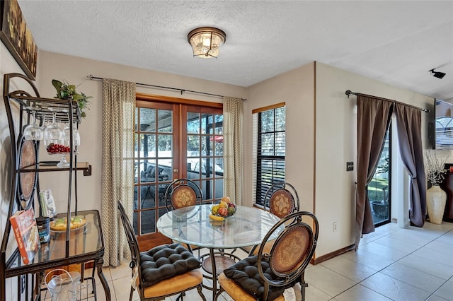 dining space with light tile patterned flooring, a textured ceiling, and french doors