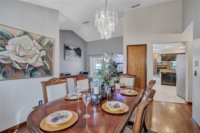 dining area featuring light tile patterned floors, a chandelier, and vaulted ceiling