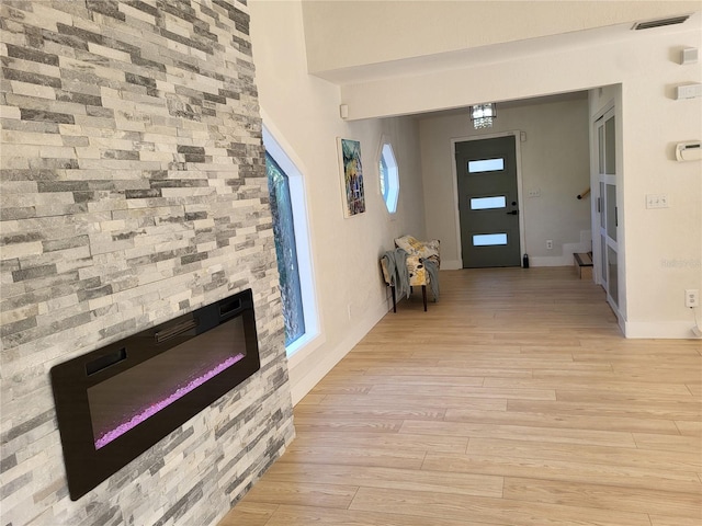 foyer with a stone fireplace and light hardwood / wood-style flooring