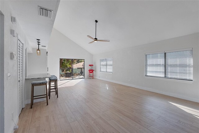 unfurnished living room with ceiling fan, light wood-type flooring, and high vaulted ceiling