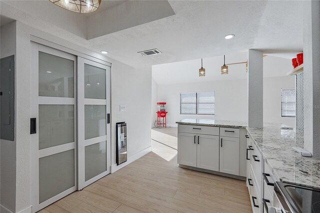 kitchen featuring white cabinets, wine cooler, light stone countertops, light wood-type flooring, and decorative light fixtures