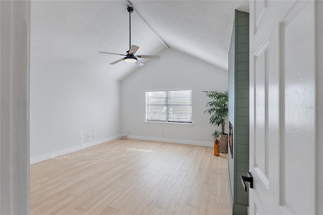 spare room featuring ceiling fan, vaulted ceiling, a textured ceiling, and light hardwood / wood-style flooring