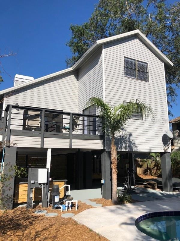 rear view of house featuring a patio area, a balcony, and a pool