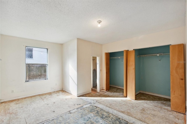 unfurnished bedroom featuring two closets and a textured ceiling