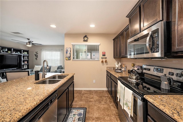 kitchen featuring sink, ceiling fan, light stone countertops, dark brown cabinetry, and stainless steel appliances